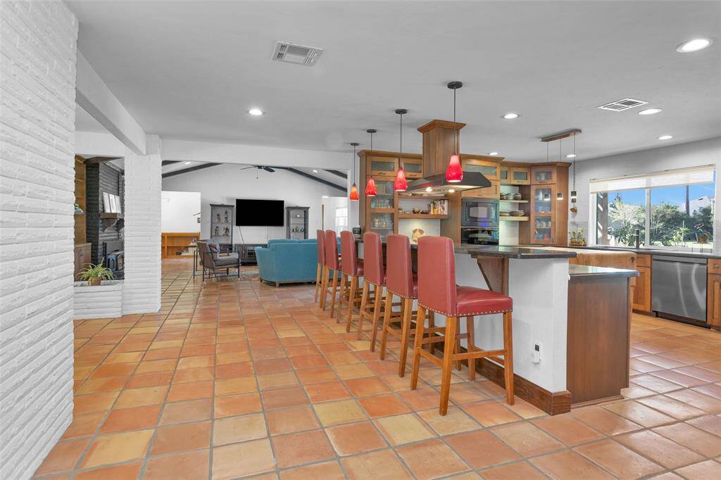 From the kitchen, you can see the timeless handmade Saltillo tile that stretches from the front door through the living room, dining area, and hallways, all the way to the primary bedroom ensuite. Look for the 'easter eggs' in some of the tiles (hint: as you enter the living room).