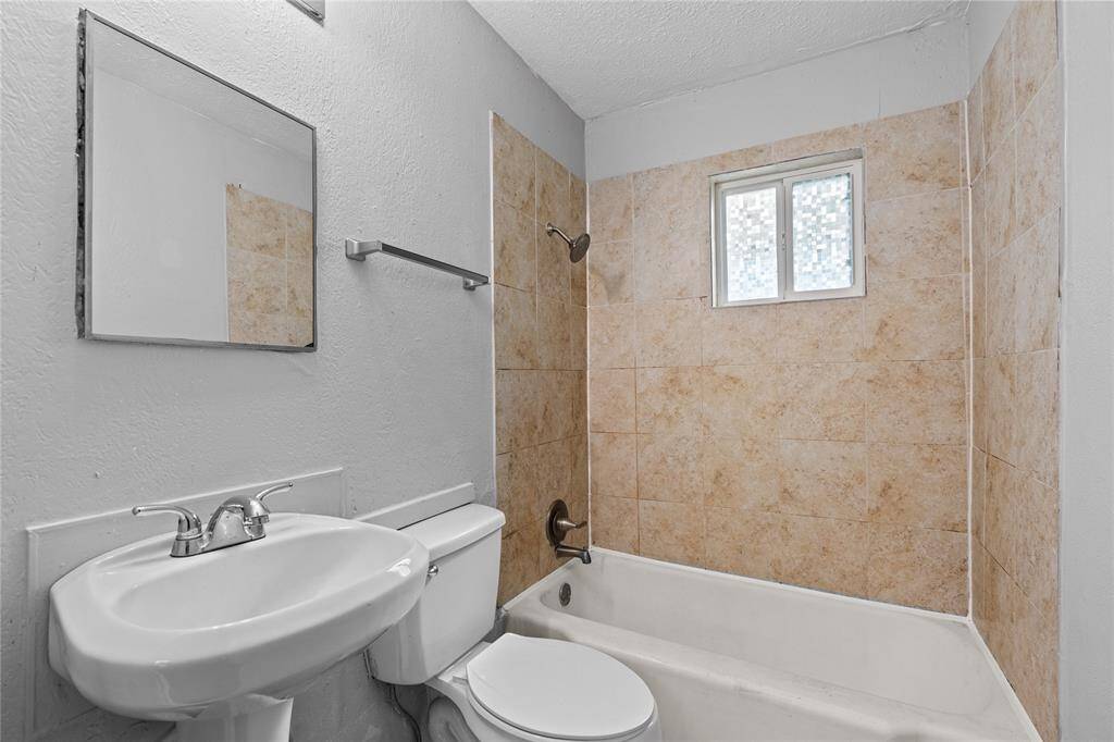 Bathroom with pedestal sink and tiled tub/shower combo