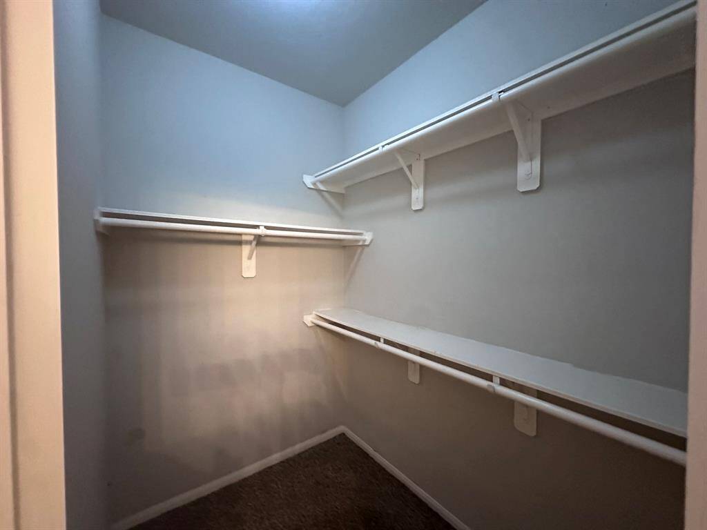 Spacious walk-in closet with multiple shelves and hanging rods, perfect for organized storage.