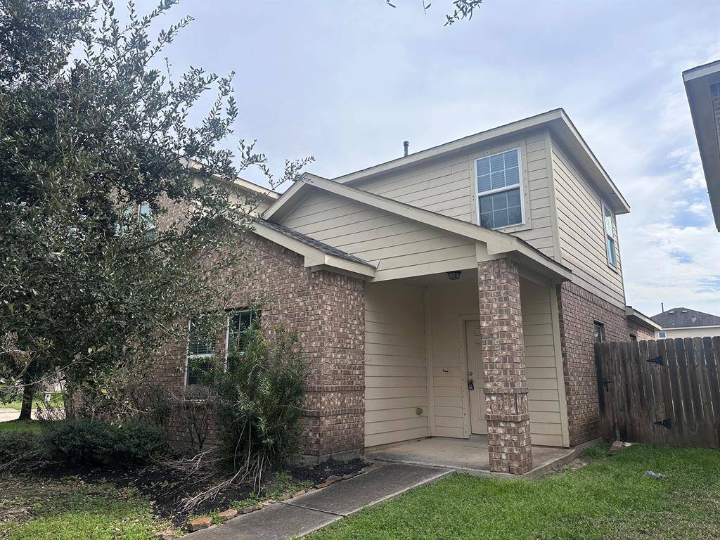 This is a two-story home with a combination of brick and siding exterior. It features a covered entrance, a small front yard with mature trees, and is situated in a residential neighborhood.