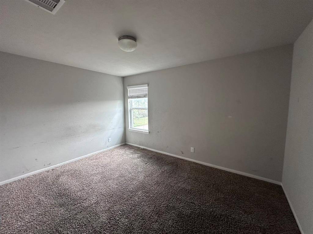 This room features neutral walls, a single window for natural light, and carpeted flooring. It’s a simple, compact space suitable for a bedroom or office.