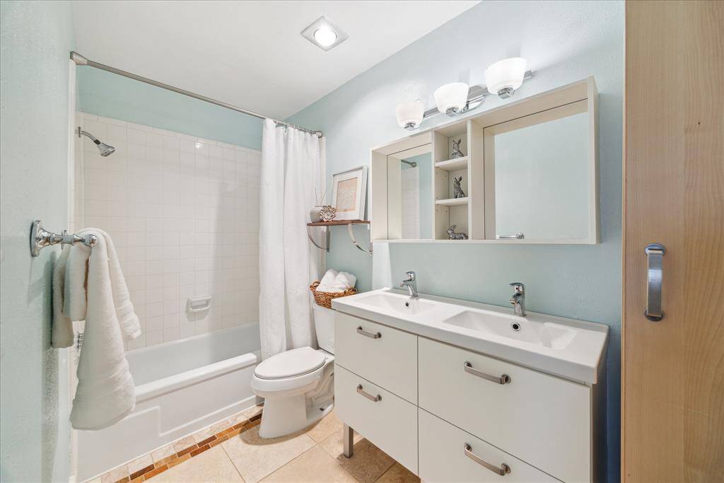 The hall bath has double-sink vanity with storage drawers, modern lighting, double mirrors, and heat lamp as well as a deep linen closet.