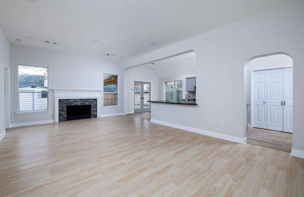 Spacious, bright living area with a fireplace and plenty of natural light! The open layout connects to the kitchen with breakfast bar, and there's easy access to the covered back patio.