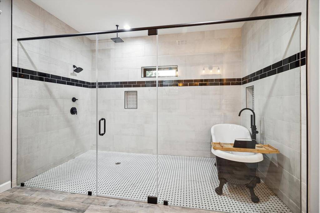 The wet room in the primary bath houses the claw-foot tub and spa-like dual “rain shower” shower heads.