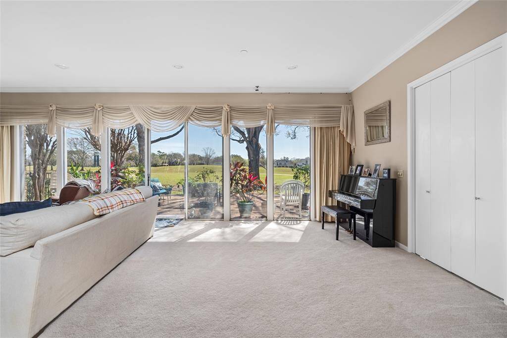 This bright and inviting living area showcases floor-to-ceiling windows that offer stunning views of the golf course and fill the space with natural light. Plush carpeting adds warmth, while the neutral-toned walls create a relaxing ambiance. Sliding glass doors lead to the outdoor patio, seamlessly blending indoor and outdoor living.