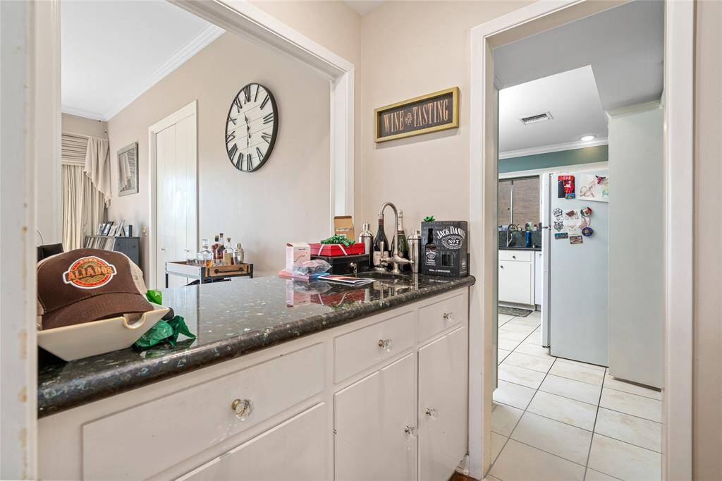 This convenient wet bar is perfect for entertaining, featuring a sleek granite countertop, built-in sink, and ample cabinet storage. Located between the main living areas and kitchen, it provides the ideal space for mixing drinks or serving guests with ease.