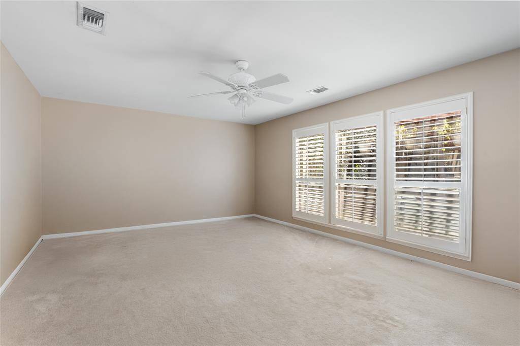 This spacious primary bedroom offers a blank canvas ready for your personal touch. With neutral tones, plush carpeting, and large windows adorned with plantation shutters, the room is filled with natural light and offers a serene retreat. The open layout provides endless possibilities to design your ideal space.