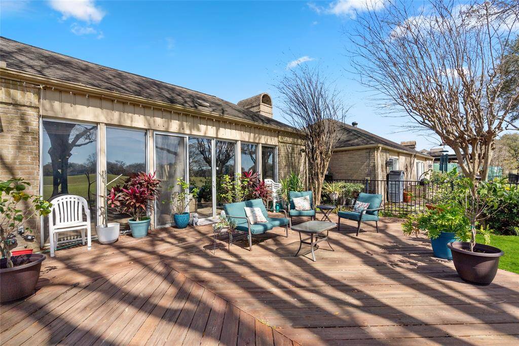 The spacious wooden deck extends from the home, providing a seamless indoor-outdoor connection with large sliding glass doors. Surrounded by mature trees and lush greenery, this outdoor retreat offers a peaceful and inviting atmosphere. The open layout allows for flexible use, perfect for entertaining or enjoying the tranquil golf course views.
