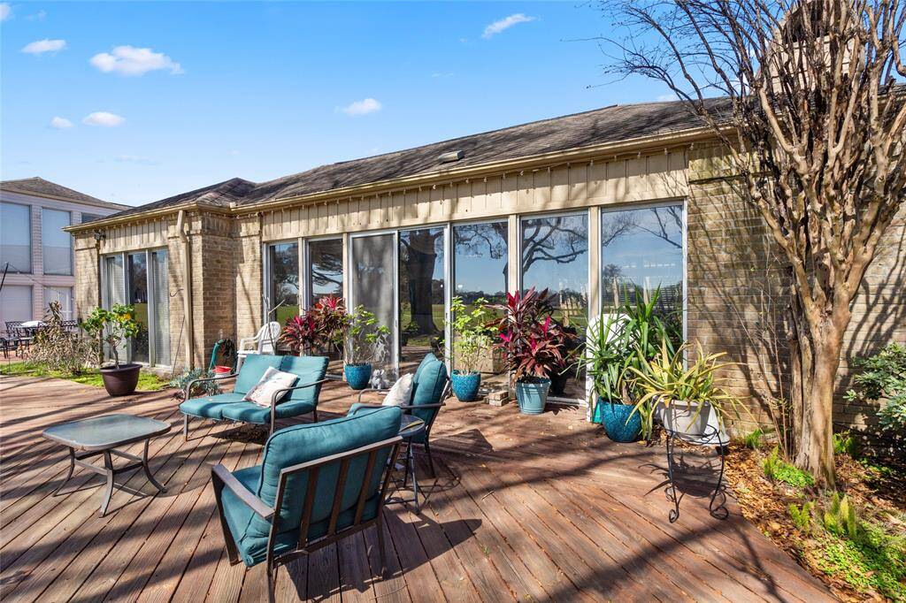 The expansive wooden deck offers a serene outdoor living space, seamlessly connecting to the home's interior through large sliding glass doors. Surrounded by lush greenery and mature trees, this area provides a perfect setting for relaxation or entertaining, with picturesque views of the golf course.
