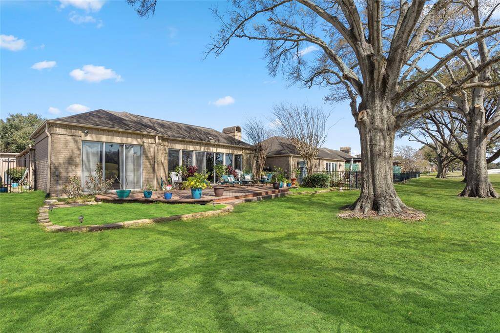 The beautifully landscaped backyard features a spacious wooden deck overlooking the lush green fairways. Mature trees provide shade and enhance the serene atmosphere, while the well-maintained lawn and garden beds add to the home's curb appeal. A perfect blend of indoor-outdoor living with picturesque golf course views.