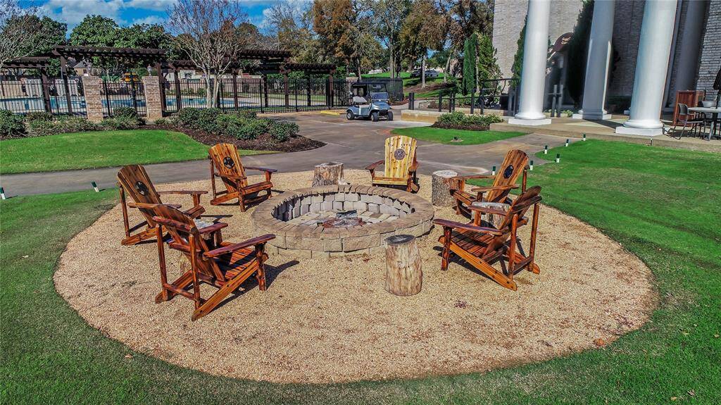 Relax and unwind in this beautifully designed outdoor gathering space, featuring a custom stone fire pit surrounded by rustic wooden chairs. Nestled within the Sugar Creek community, this inviting amenity offers a perfect setting for evening conversations and social gatherings. Just steps away, enjoy the lush landscaping, pergola-covered seating areas, and a sparkling pool. Experience the charm and tranquility of Sugar Creek living!