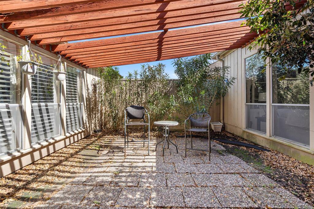 This charming center courtyard offers a private outdoor retreat, complete with a pergola providing partial shade. Surrounded by lush greenery and enclosed for added privacy, the space is ideal for relaxing or enjoying a morning coffee. The pebble-stone patio enhances the natural ambiance, creating a cozy and inviting atmosphere.