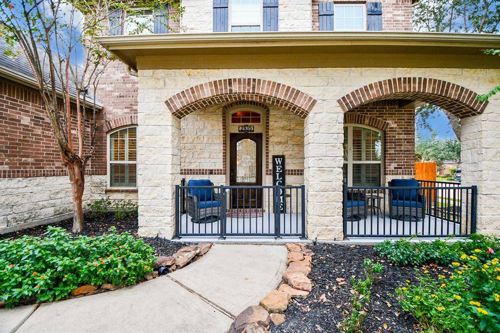 Step into elegance through a wrought iron gate leading to a charming, covered front patio. This inviting space is framed by a stunning stone elevation, blending style and functionality to create the perfect spot for relaxing or greeting guests.
