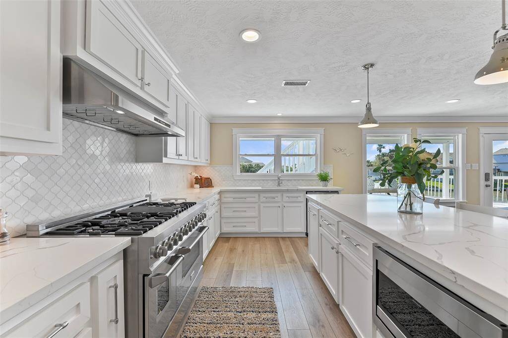 The kitchen is complete with shaker cabinets, quartz countertops, tile backsplash, & under cabinet lighting.