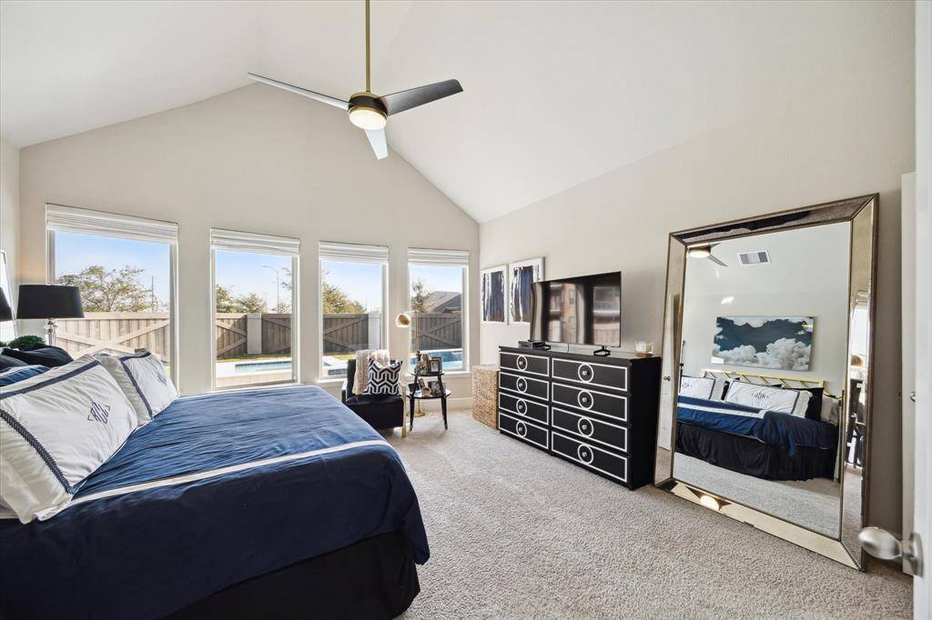 This spacious primary bedroom features high ceilings, large windows with natural light, and a view of the backyard pool, creating a bright and inviting retreat.  Located on the 1st floor.