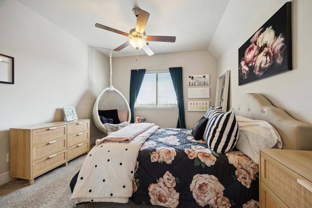 This cozy secondary bedroom has a ceiling fan, soft carpeting, and a window with curtains, creating a welcoming and relaxing atmosphere that overlooks the pool.