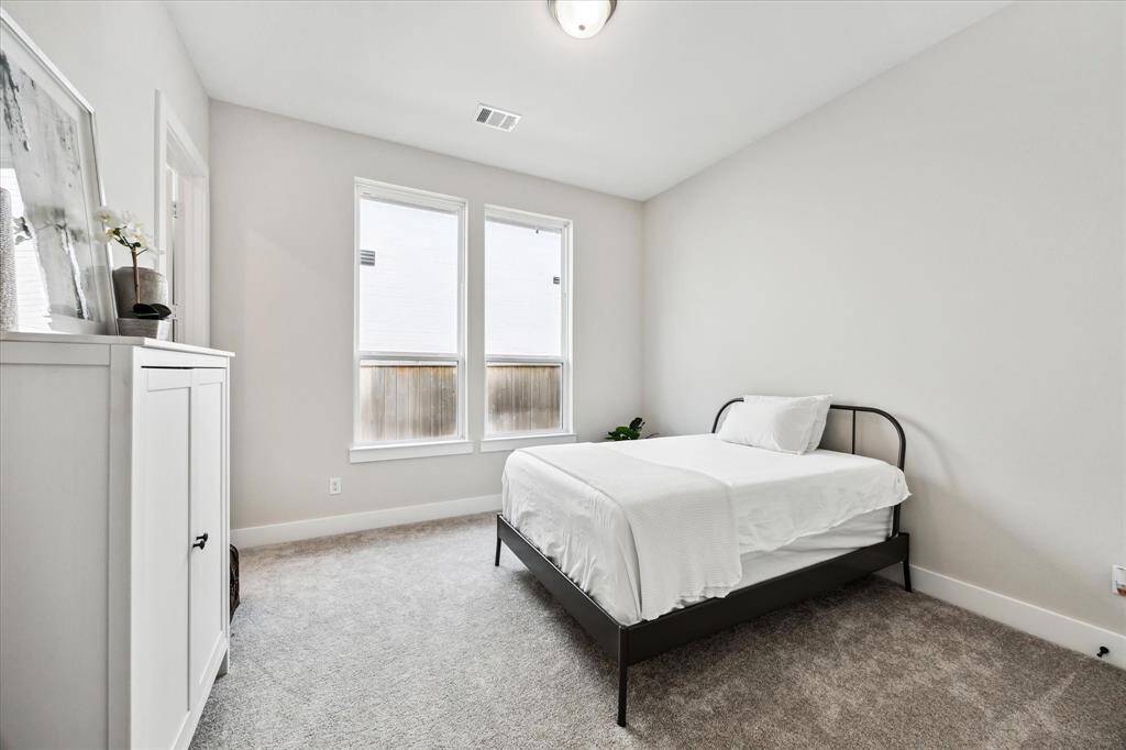 This bright secondary bedroom features neutral tones, a large closet, and two large windows for natural light.