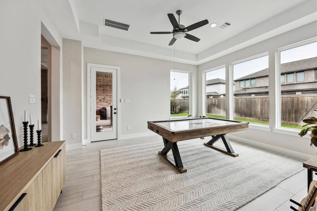 Bright and Spacious Gameroom with large windows and neutral tones. Easy outdoor access through a glass door. Ideal for entertainment or relaxation.