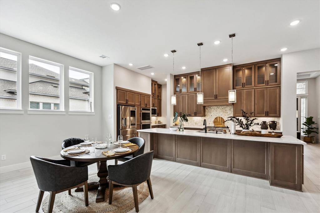 A spacious, modern kitchen with high ceilings and ample natural light. It features high-end cabinetry, a large island with pendant lighting, and a cozy dining area, creating a perfect blend of style and functionality.