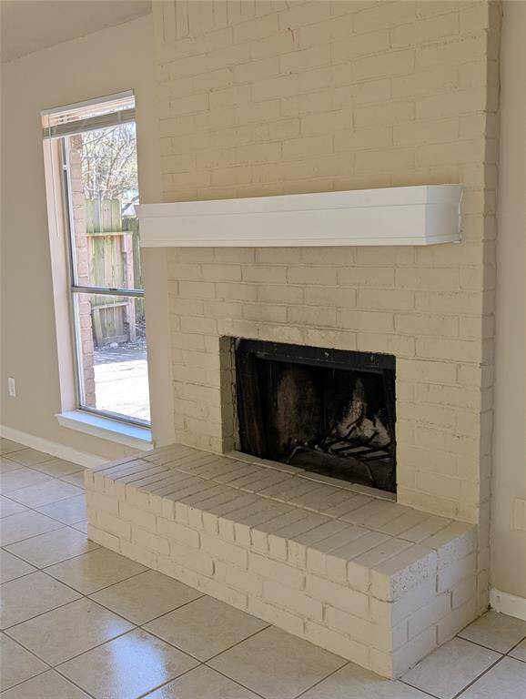 Fireplace with large hearth and mantel is flanked by windows.