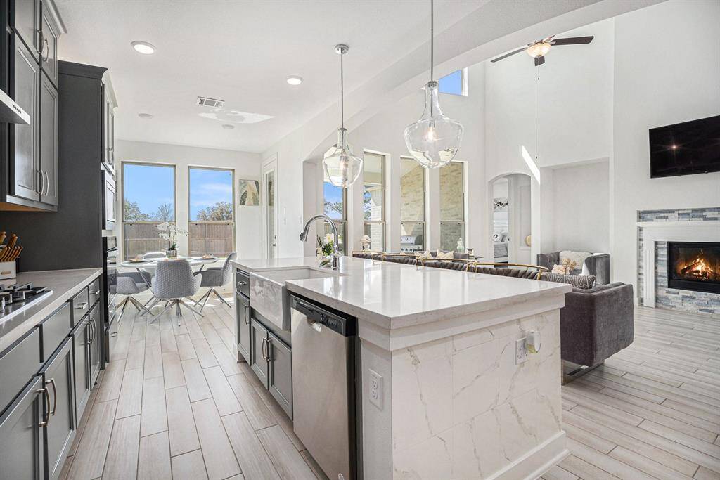 The beautifully designed kitchen features sleek stainless steel appliances, gas cook top, and a charming farmhouse sink.