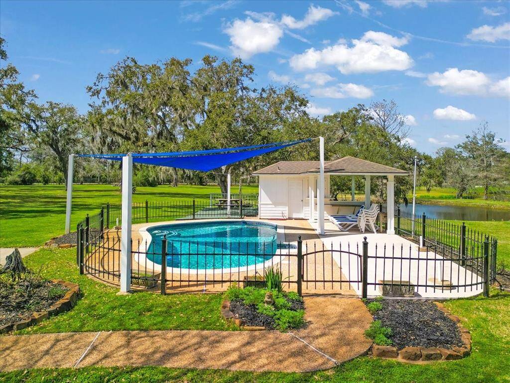 Fenced-in pool area with pool shade and a pool equipment room.