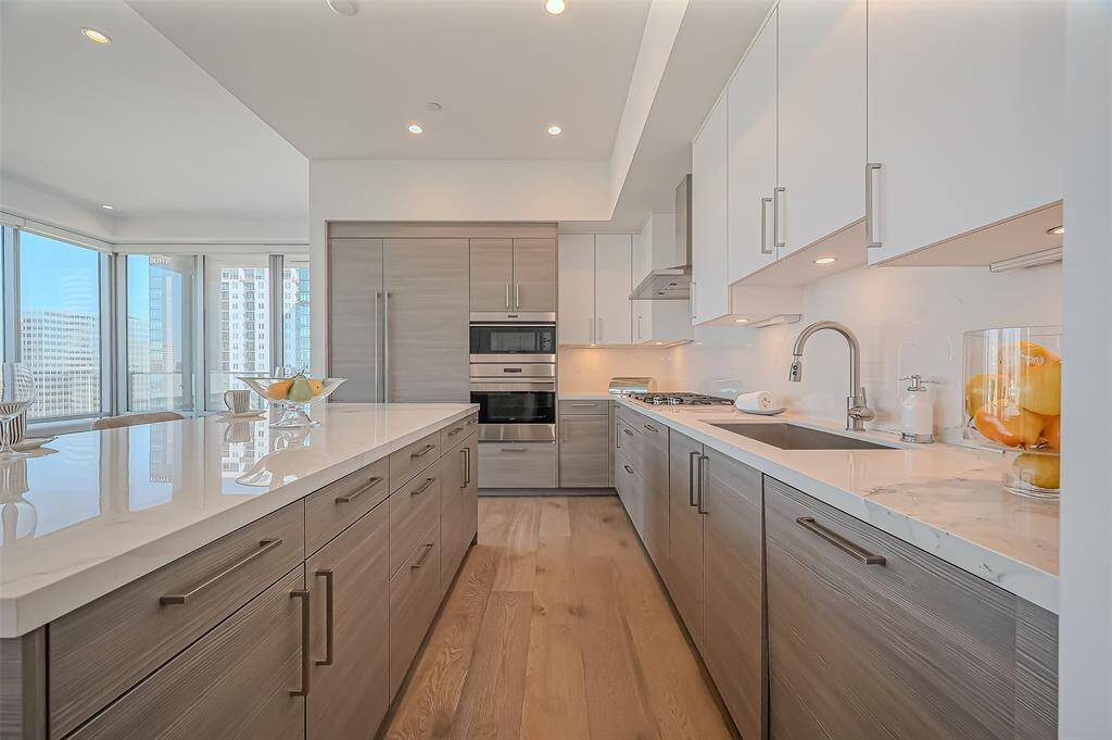 Spacious island with seating, and contemporary lighting. It boasts stainless steel appliances, ample storage, and elegant marble countertops, creating a bright and inviting space.
