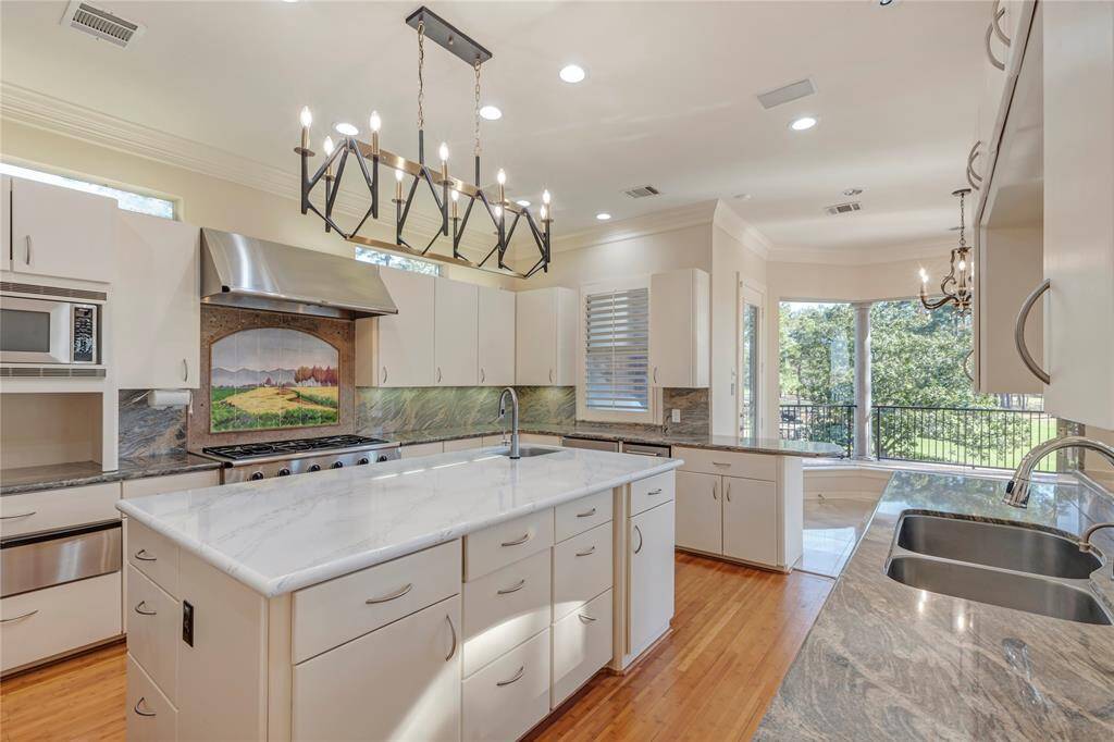 Kitchen Dacor 6 gas grill cook top, warming draw, double ovens, microwave, garage appliance area, ice machine, beverage refrigerator, trash compactor, double sinks with garbage disposals, 2023 quarte island counter top, lighting fixture, and 2023 Subzero refrigerator,