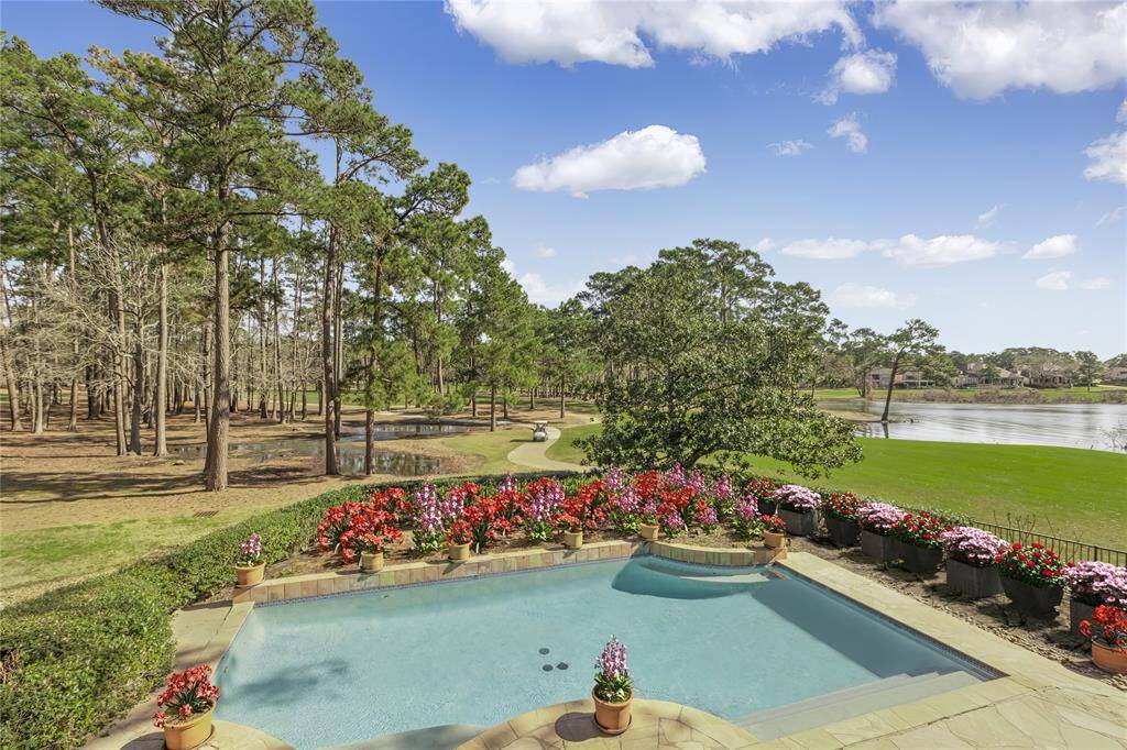 Pool area with golf course views and Lake Conroe.  Flowers have been virtually staged.
