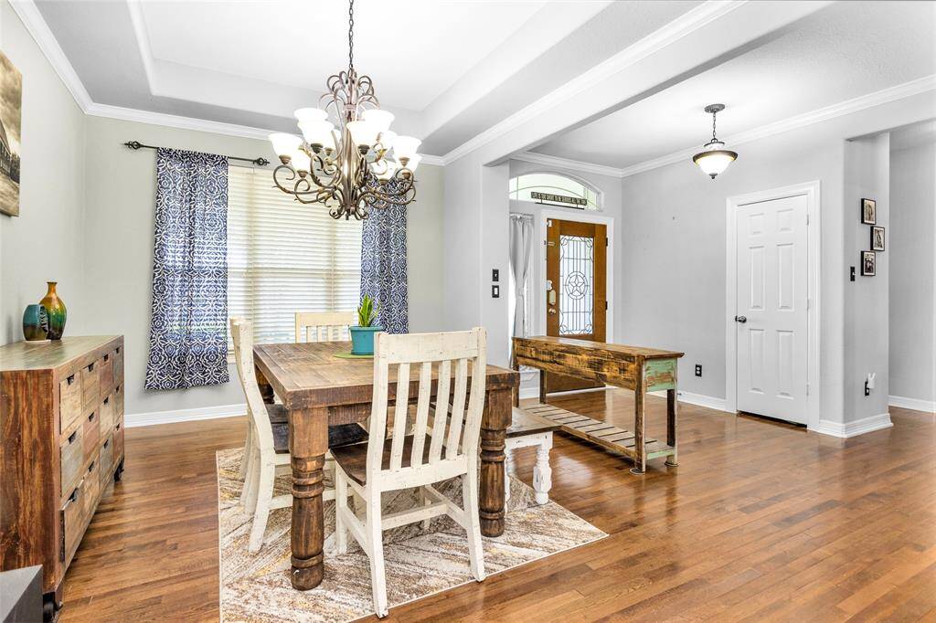 The dining room features tray ceiling, rich-toned wood floors, and room for buffet.