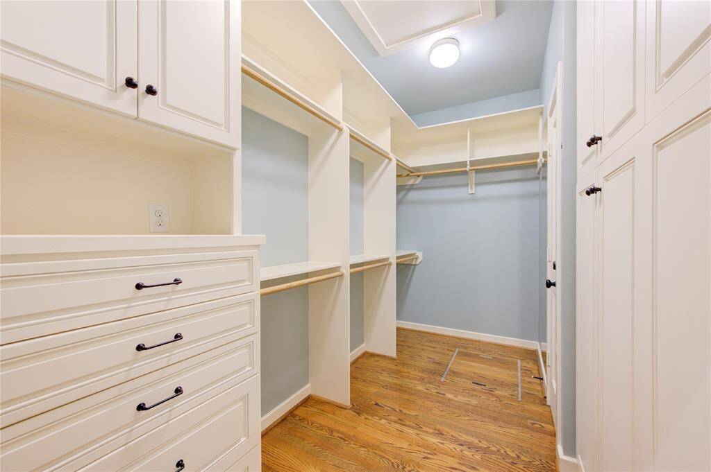 The primary bedroom includes a spacious walk-in closet, designed to accommodate an extensive wardrobe. This well-organized closet features custom built-in shelving, hanging racks, and drawers, providing ample storage and organization options.