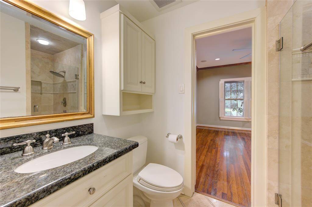 This well-appointed secondary bathroom features elegant granite countertops and a modern walk-in shower with sleek tile work and a glass door. The design combines style and functionality, with high-quality fixtures and ample storage space. This bathroom provides a sophisticated touch while offering convenience and comfort for family members and guests.