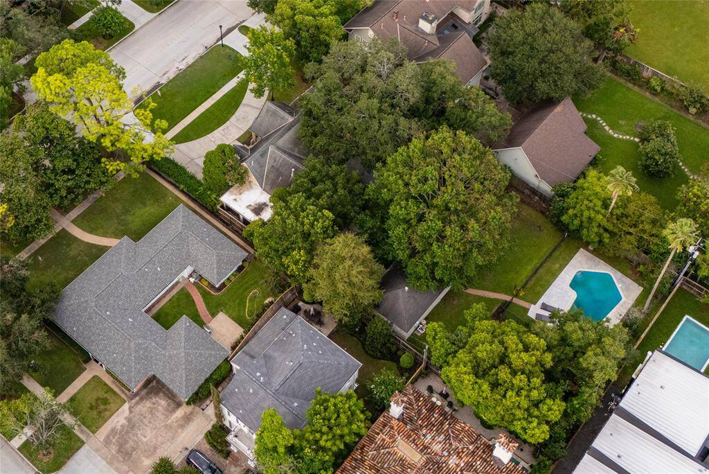 Aerial view capturing the expansive backyard oasis featuring a sparkling pool, extensive patio area, and outdoor seating. The lush landscaping, mature trees, and privacy fence create a serene retreat perfect for relaxation and entertaining guests.