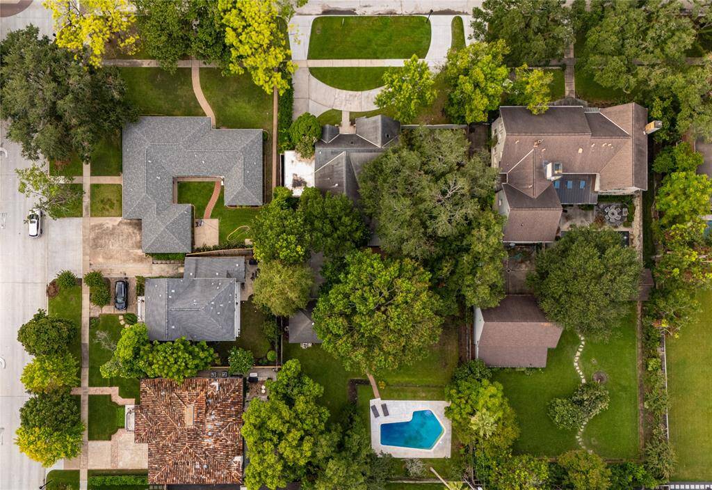 Aerial shot focusing on the backyard oasis, featuring the sparkling pool, extended deck, and lush landscaping. This view highlights the outdoor living spaces and the privacy offered by the mature trees and fencing.