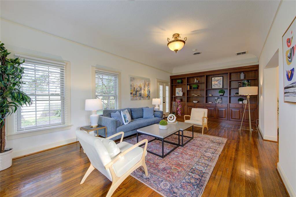 A stunning wall of built-ins provides ample storage and display options, perfect for showcasing your favorite books, decorative items, and family photos. Large windows fill the room with natural light, illuminating every corner and offering picturesque views of the lush backyard.