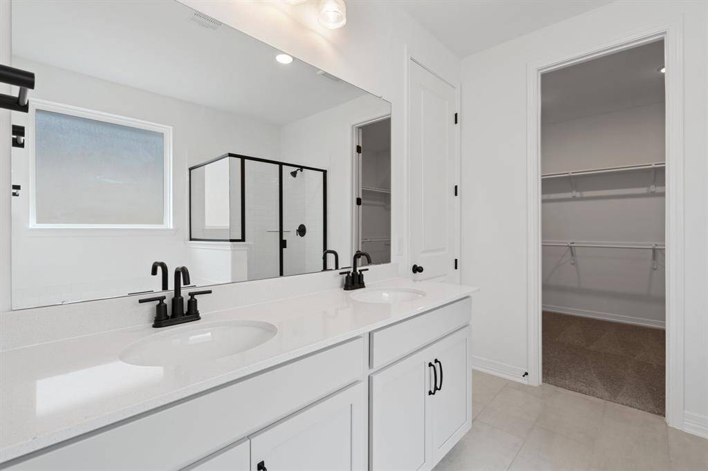 The en-suite bathroom offers a spa-like atmosphere with its elegant design, high end finishes, and tasteful lighting, creating a retreat within your own home.