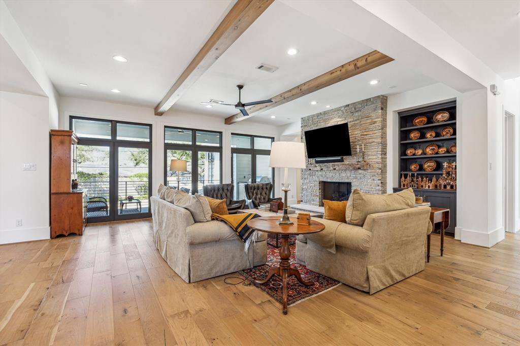 Spacious family room with French doors open to the back porch. The primary suite is located to the left of the fireplace and the downstairs guest suite is located down hall right of the fireplace.