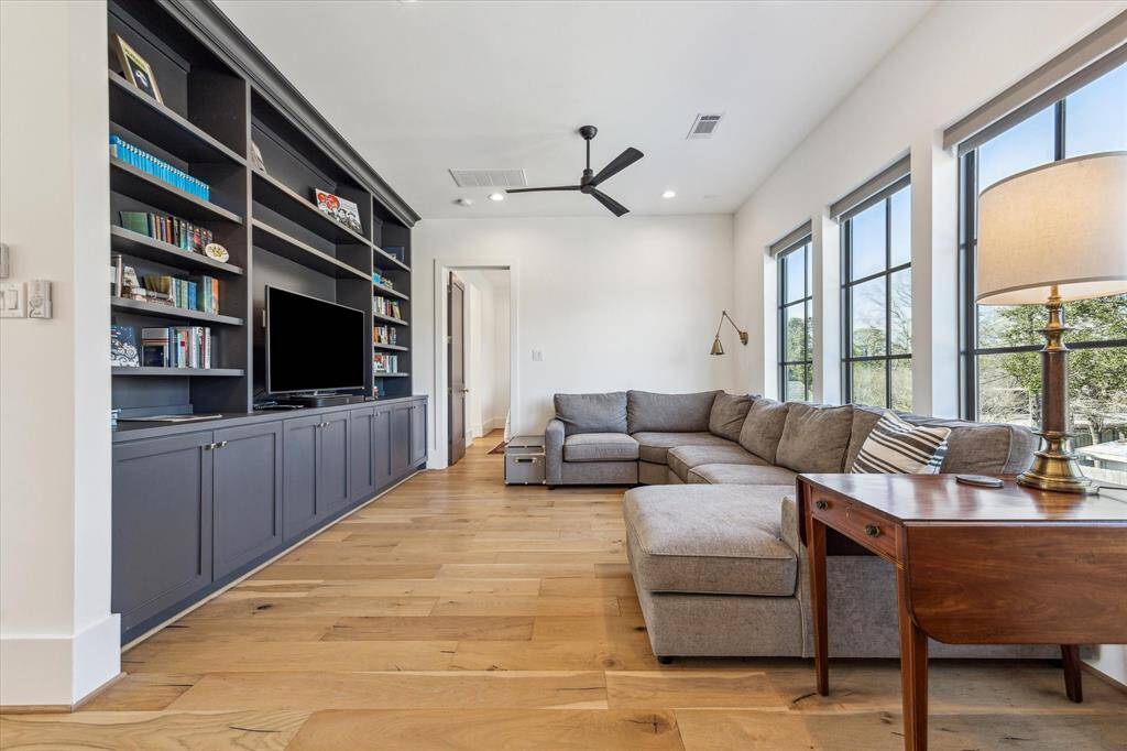 Upstairs den or gameroom with hardwood floors, built ins and walls of windows overlooking backyard.