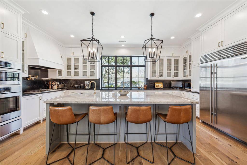 Like something out of Architectural Digest.  This is a dream kitchen with massive quartzite island, glass front cabinets with brass pulls, stainless Subzero and Bosch appliances.