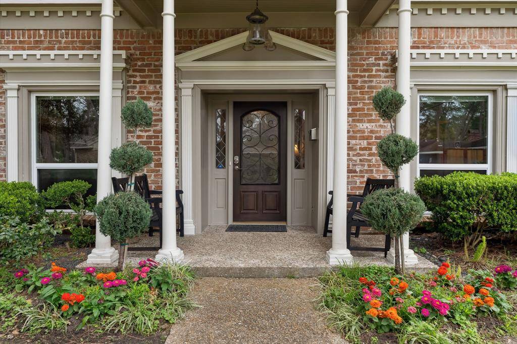 Welcome to 607 Briarpark Drive, where classic architectural details meet beautifully manicured landscaping. This inviting front entrance showcases elegant white columns, a grand pediment, and intricate brickwork, offering a warm and stately first impression. The wrought iron-accented front door is framed by decorative glass sidelights, adding both sophistication and natural light to the entryway. Vibrant flower beds and neatly trimmed topiaries create a picturesque setting.