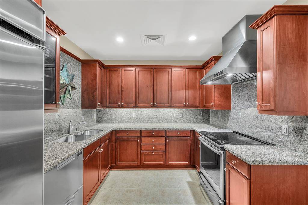 Kitchen features built-in refrigerator and commercial style exhaust vent hood.  In 2023 the range and dishwasher were replaced. The dishwasher is a Fisher Paykel double drawer unit.  Directly behind camera shot is Walk-In Pantry.