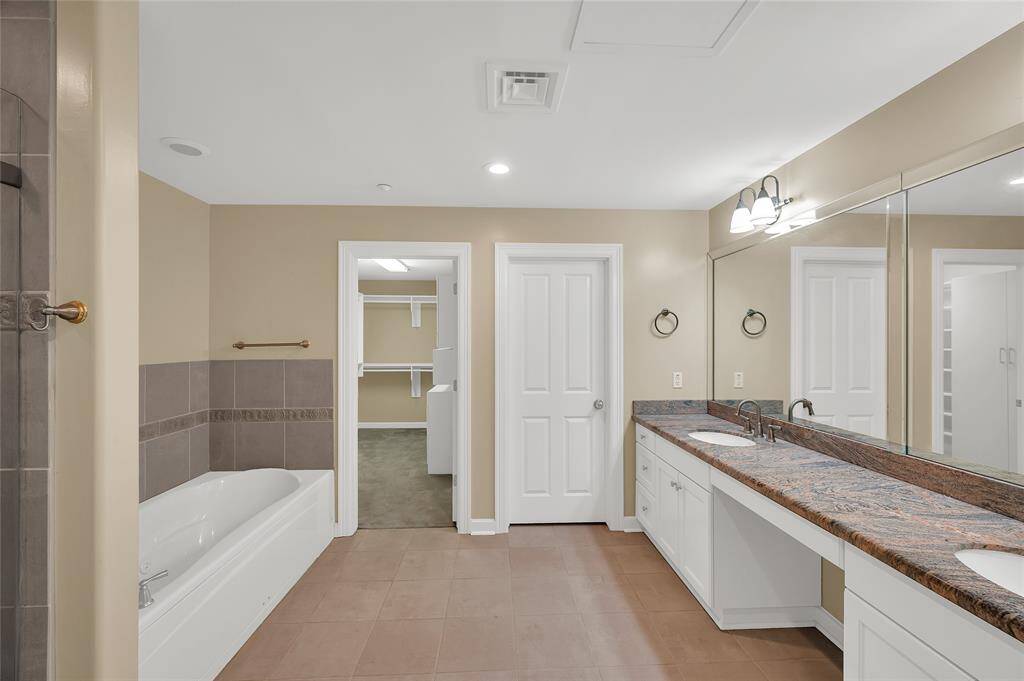 Spa-like Bathroom has extended vanity with dual sinks and granite tops. Walk-in shower with glass enclosure and separate jetted soaking tub. Facing closed door is private toilet room.