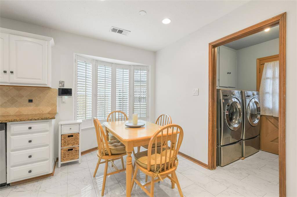 The neutral tones and elegant tile flooring provide a seamless flow from the kitchen, creating a warm and inviting space perfect for casual meals or coffee breaks. Just beyond, a dedicated laundry area with modern appliances adds to the home's functionality. This beautifully designed nook seamlessly blends comfort and practicality—making everyday living effortless!