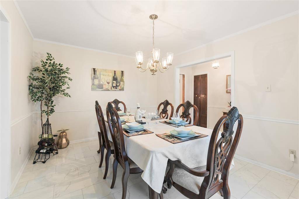 The graceful chandelier casts a warm glow over the beautifully set dining table, creating the perfect ambiance for entertaining guests or enjoying intimate family dinners.