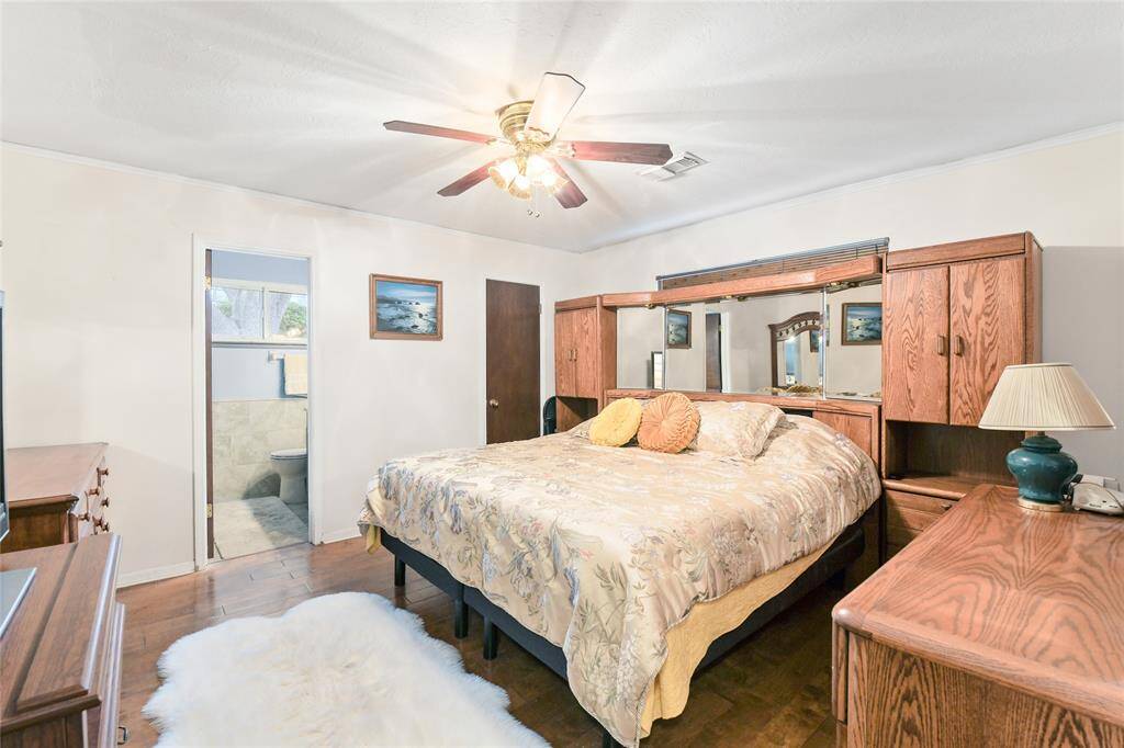 Unwind in this comfortable and inviting primary bedroom, featuring warm hardwood flooring, soft neutral tones, and a ceiling fan for year-round comfort.