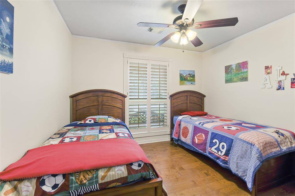 This delightful secondary bedroom offers a warm and inviting atmosphere, perfect for kids, guests, or a flexible space to suit your needs. Rich hardwood flooring, neutral walls, and a stylish ceiling fan enhance both comfort and functionality. The large window with elegant plantation shutters allows plenty of natural light while offering privacy and a classic touch.
