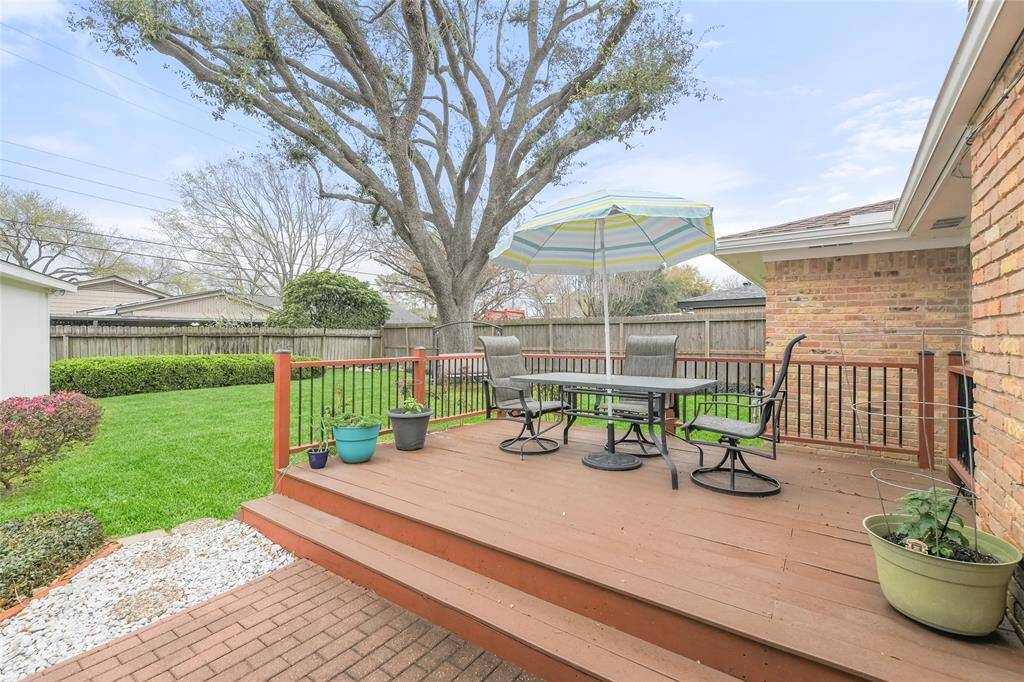 Step outside and enjoy seamless indoor-outdoor living in this expansive backyard retreat. The elevated deck with stylish railing is perfect for dining al fresco, entertaining guests, or simply unwinding under the shade of a large umbrella.