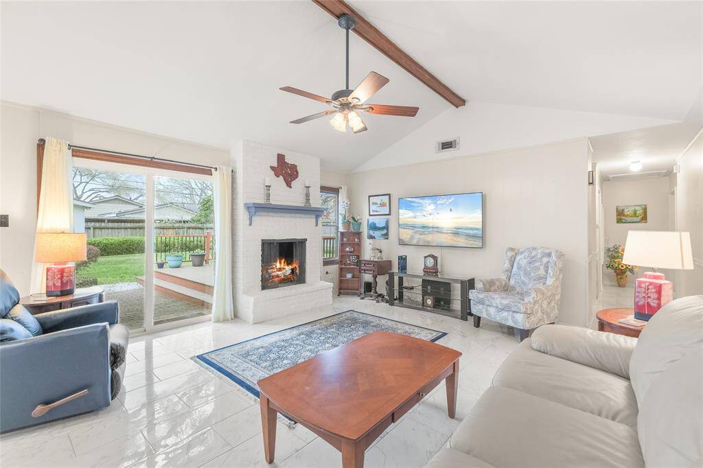 Large windows and sliding doors flood the room with natural light, seamlessly connecting indoor and outdoor living. The elegant tile flooring, neutral color palette, and thoughtfully designed layout create a warm and welcoming ambiance.