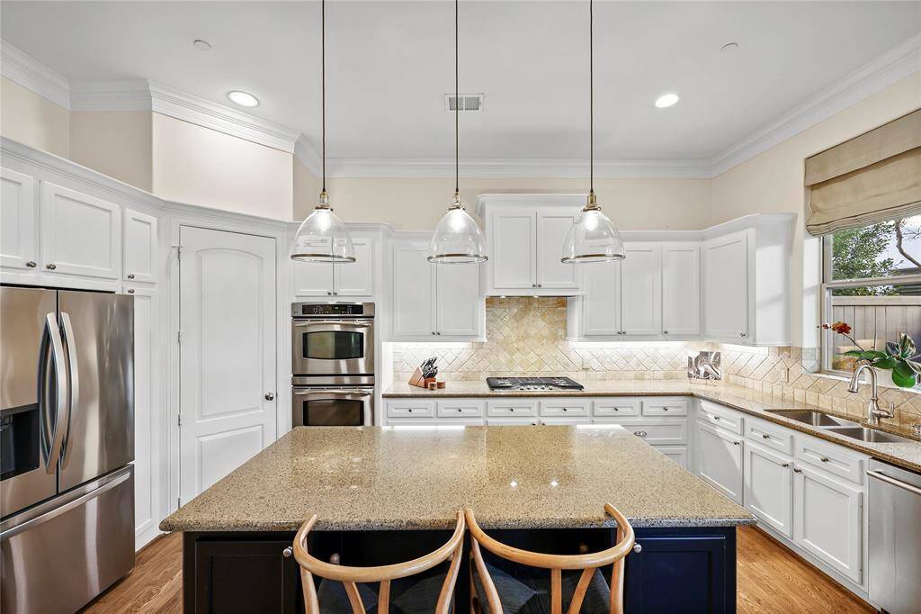 A spacious island with bar seating serves as the centerpiece, illuminated by stylish pendant lighting