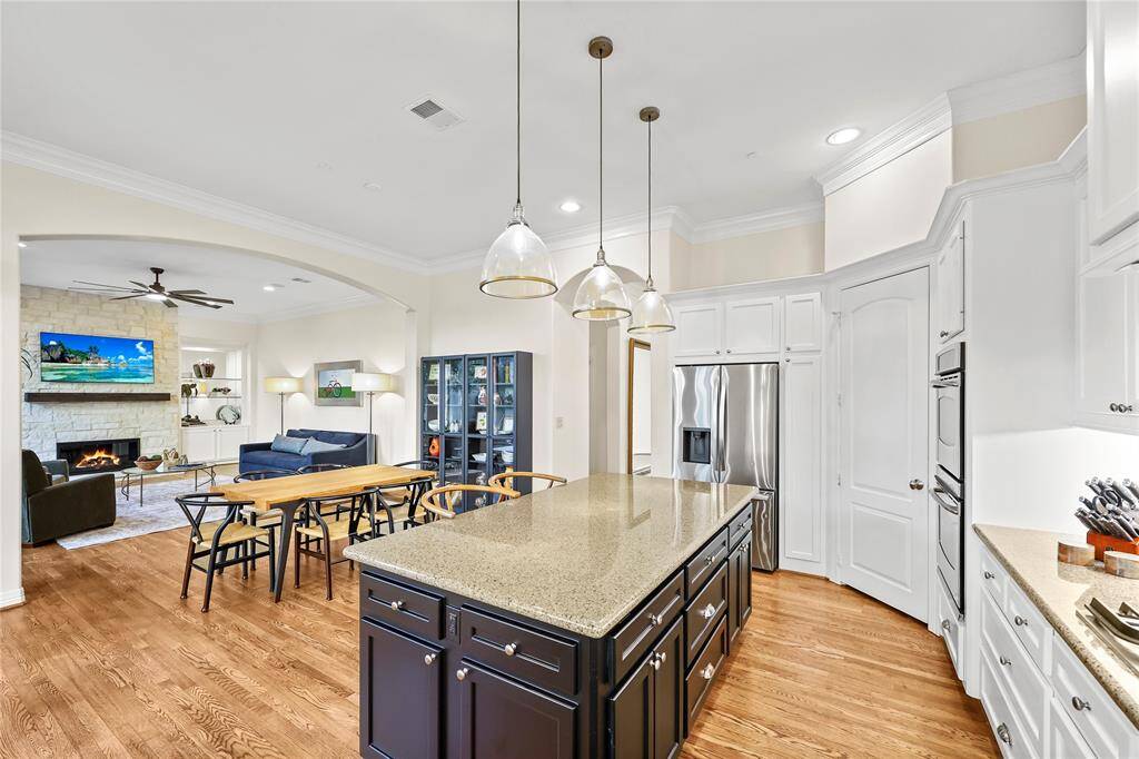 Featuring a large central island with bar seating, elegant pendant lighting, ample cabinet storage, the kitchen is both stylish and functional
